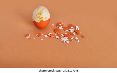 Semi-purified painted orange egg and there are a lot of eggshells nearby on a brown background. Abstract composition. Easter holiday concept. - Powered by Shutterstock