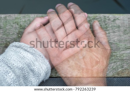 Semi-transparent man's hand on a woman's hand as a sign of farewell by separation or death