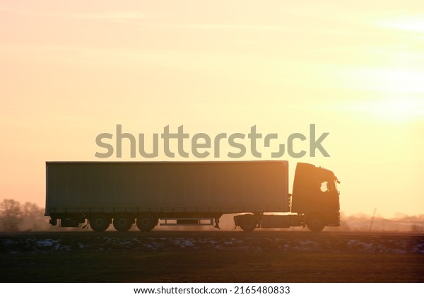 Semi-truck\
with cargo trailer driving on highway hauling goods in evening.\
Delivery transportation and logistics\
concept