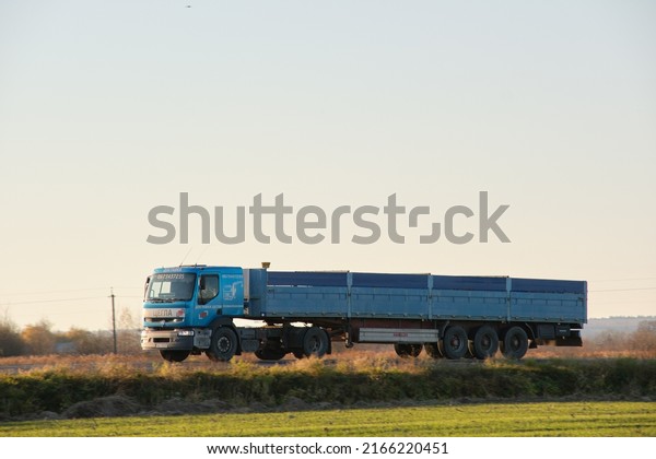 Semi-truck with cargo trailer driving\
on highway hauling goods in evening. Delivery transportation and\
logistics concept. Kyiv, Ukraine - October 12,\
2021.