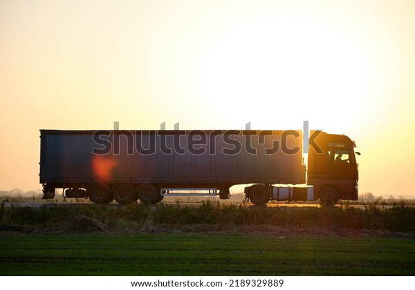 Semi-truck\
with cargo trailer driving on highway hauling goods in evening.\
Delivery transportation and logistics\
concept