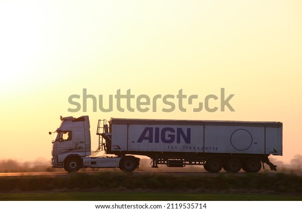 Semi-truck with tipping cargo trailer transporting\
sand from quarry driving on highway hauling goods in evening.\
Delivery transportation and logistics concept. Kyiv, Ukraine -\
October 12, 2021.