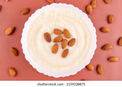 Semolina Porridge With Almonds In A White Plate (bowl) On A Pink (coral, Brown) Background Close-up. Baby Food. Contains Gluten In The Composition.