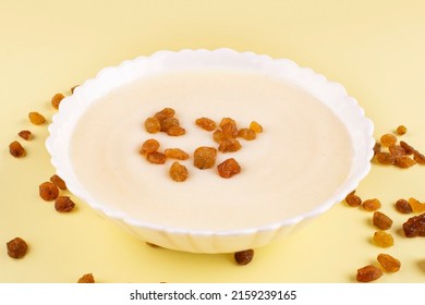 Semolina Porridge With Raisins In A White Plate (bowl) On A Yellow Background Close-up. Side View. Baby Food. Contains Gluten In The Composition.