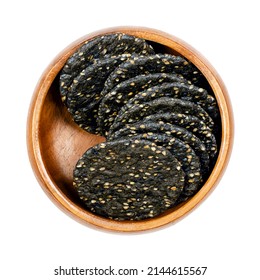 Senbei, Japanese Sesame Crackers, In A Wooden Bowl. Crispy Macrobiotic Crackers, Made Of Brown Rice, Black Sesame Seeds And Soy Sauce. Crunchy Snack. Close-up From Above, Isolated, Macro Food Photo.