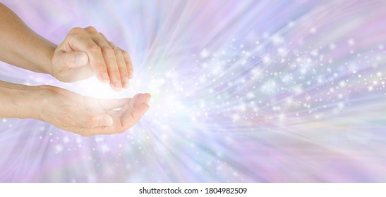 Sending your beautiful high frequency healing energy - female cupped hands with white light and flowing sparkles on lilac energy field background with copy space 
