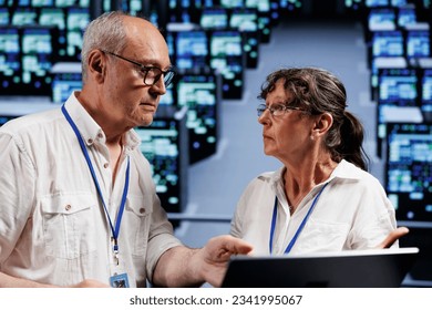 Senescent computer operators working to maintain uptime in high tech location. Skillful experts brainstorming solutions to data center server rigs crashing, trying to fix components