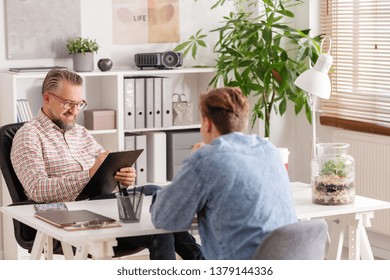 Senior Account Manager And Young Man During Job Interview In Small Firm