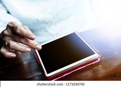 Senior Adult Aging Retire Elderly Woman Chat Texting With Friend, Family, Play Game, Reading On Dining Table Relax And Socialize Using Tablet, Ipad, Internet Online Digital Technology To Communicate 