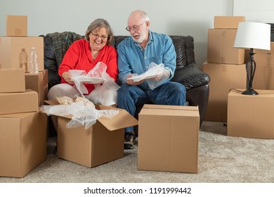 Senior Adult Couple Packing or Unpacking Moving Boxes. - Powered by Shutterstock