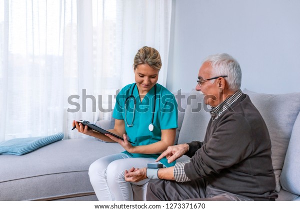 Senior Adult man Learning\
From Female Doctor to Use Blood Pressure Machine. Smiling female\
nurse showing clipboard to happy senior man after measuring blood\
pressure 