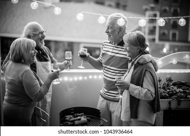 senior adult people group in leisure activity doing barbeque bbq on the rooftop terrace at home with mountain view. meal and wine for two men and two women having fun together under the sunlight  - Powered by Shutterstock