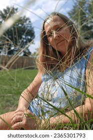 senior adult woman portrait sitting in tall grass - Shutterstock ID 2365301793
