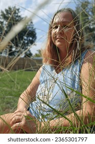 senior adult woman portrait sitting in tall grass - Shutterstock ID 2365301797