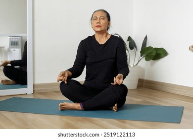 Senior adult woman practicing yoga and doing breathing practice at home. Mindfulness meditation concept. - Powered by Shutterstock