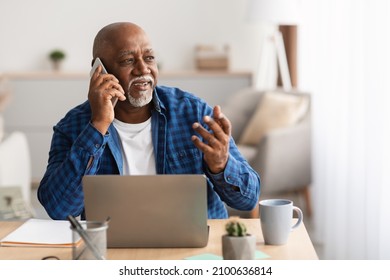 Senior African American Businessman Talking On Mobile Phone Sitting At Laptop Working Online Looking Aside In Modern Office Indoor. Business Communication Concept