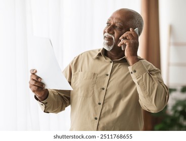 Senior African American Businessman Talking On Cellphone Holding Paper Document Looking Aside Standing Indoors. Freelance Career In Older Age. Mobile Communication Concept - Powered by Shutterstock