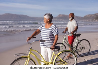 Senior african american couple with bicycles standing on the beach. travel vacation retirement lifestyle concept