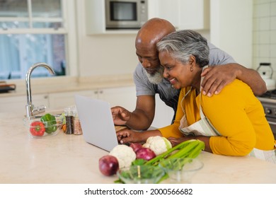 Senior African American Couple Cooking Together In Kitchen Using Laptop. Retreat, Retirement And Happy Senior Lifestyle Concept.