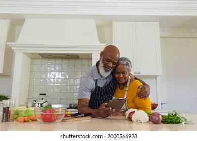 Senior african american couple cooking together in kitchen using tablet. retreat, retirement and happy senior lifestyle concept. - Powered by Shutterstock