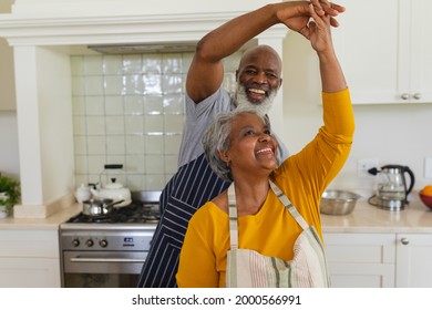 Una pareja adulta afroamericana bailando juntos en la cocina sonriendo. retiro, retiro y feliz concepto de estilo de vida senior.