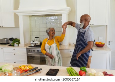 Senior african american couple dancing together in kitchen smiling. retreat, retirement and happy senior lifestyle concept. - Powered by Shutterstock