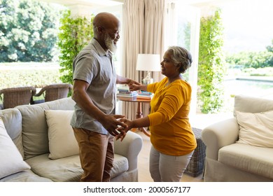 Senior african american couple dancing together in living room smiling. retreat, retirement and happy senior lifestyle concept.
