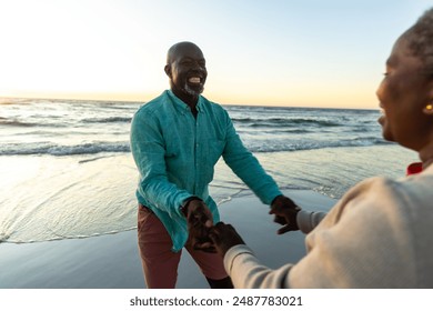 Senior African American couple enjoys a playful moment on the beach, with copy space. Their laughter and connection highlight a joyful outdoor experience. - Powered by Shutterstock