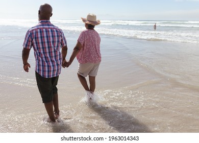 Senior African American Couple Holding Hands Walking On The Beach. Travel Vacation Retirement Lifestyle Concept