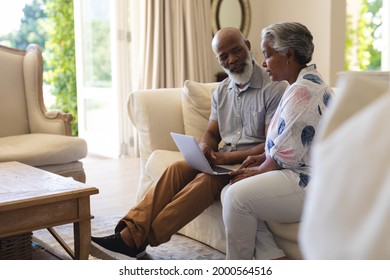 Una pareja norteamericana de alto rango sentada en un sofá usando una laptop y hablando. retiro, retiro y feliz concepto de estilo de vida senior.
