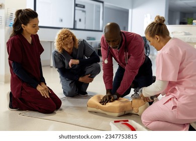 Senior african american male doctor with diverse trainee doctors learning cpr on model at hospital. Hospital, traineeship, medicine, healthcare and work, unaltered. - Powered by Shutterstock