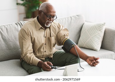 Senior African American Male Measuring Arterial Blood Pressure Having Hypertension Symptom Sitting On Couch At Home. High Blood-Pressure, Health Problem Concept