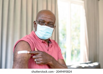 Senior afrikanischer Mann in Gesichtsmaske, der nach der Impfung Gips zeigt. Seniorengesundheit und Lebensstil während der Covid 19 Pandemie.