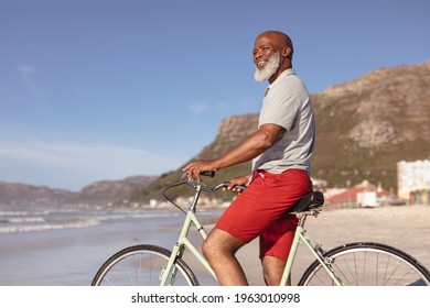 Senior African American Man Sitting On Bicycle Smiling On The Beach. Travel Vacation Retirement Lifestyle Concept