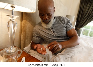 Senior African American Man Spending Time At Home, Lying In Bed, Taking Medication. Isolating During Coronavirus Covid 19 Quarantine Lockdown.