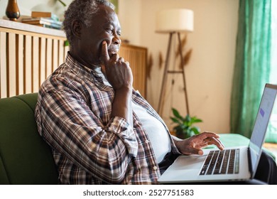 Senior African American man using laptop on couch at home - Powered by Shutterstock