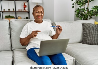 Senior african american woman having telemedicine measuring temperature at home - Powered by Shutterstock