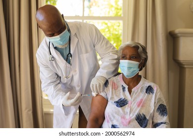 Senior African American Woman And Male Doctor In Face Masks, Woman Receiving Vaccination. Retirement And Senior Lifestyle During Covid 19 Pandemic Concept.