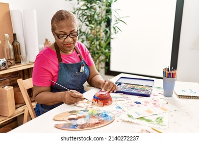 Senior african american woman smiling confident painting clay ceramic at art studio - Powered by Shutterstock