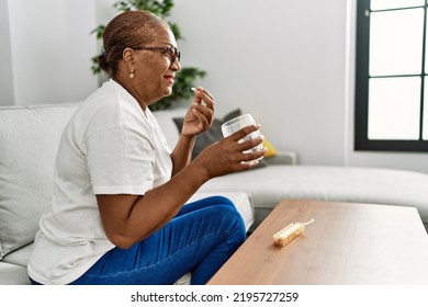 Senior african american woman smiling confident taking pills at home - Powered by Shutterstock