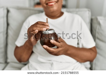 Senior african american woman smiling confident drinking mate infusion at home