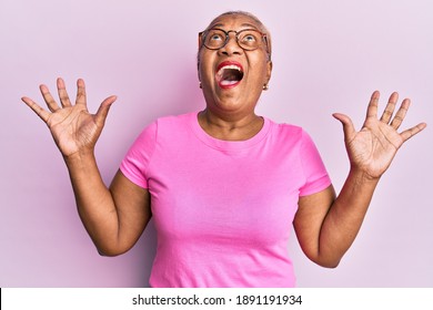 Senior African American Woman Wearing Casual Clothes And Glasses Crazy And Mad Shouting And Yelling With Aggressive Expression And Arms Raised. Frustration Concept. 