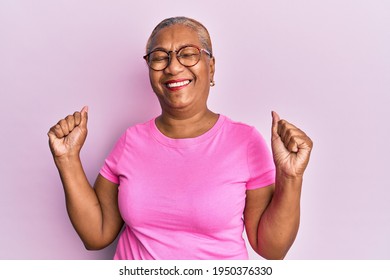 Senior african american woman wearing casual clothes and glasses very happy and excited doing winner gesture with arms raised, smiling and screaming for success. celebration concept.  - Powered by Shutterstock