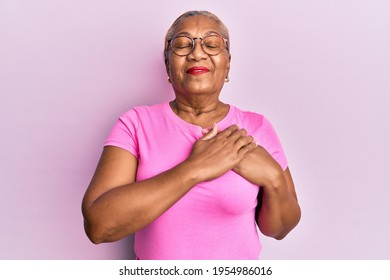 Senior african american woman wearing casual clothes and glasses smiling with hands on chest with closed eyes and grateful gesture on face. health concept.  - Powered by Shutterstock