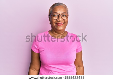 Senior african american woman wearing casual clothes and glasses looking positive and happy standing and smiling with a confident smile showing teeth 
