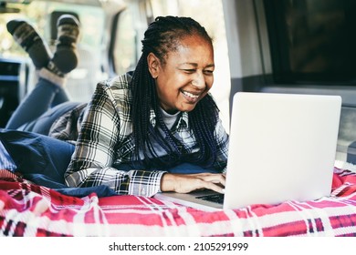 Senior african woman having fun inside camper van using laptop computer - Focus on face