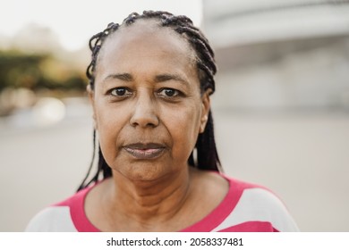 Senior african woman looking at camera outdoor in the city - Focus on face - Shutterstock ID 2058337481