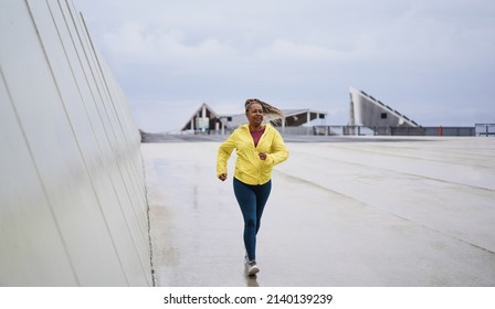 Senior African Woman Running Outdoor In The City During Rainy Day - Focus On Face