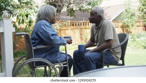 Senior African Woman In Wheel Chair Outdoors With Husband