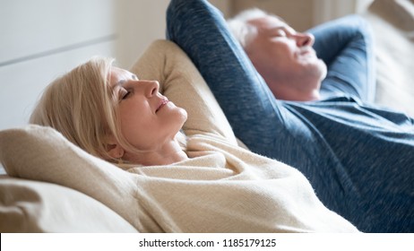 Senior aged couple relaxing on comfortable sofa together breathing fresh air at home, calm old mature man and woman enjoying no stress free weekend peaceful rest having healthy daytime nap on couch - Powered by Shutterstock